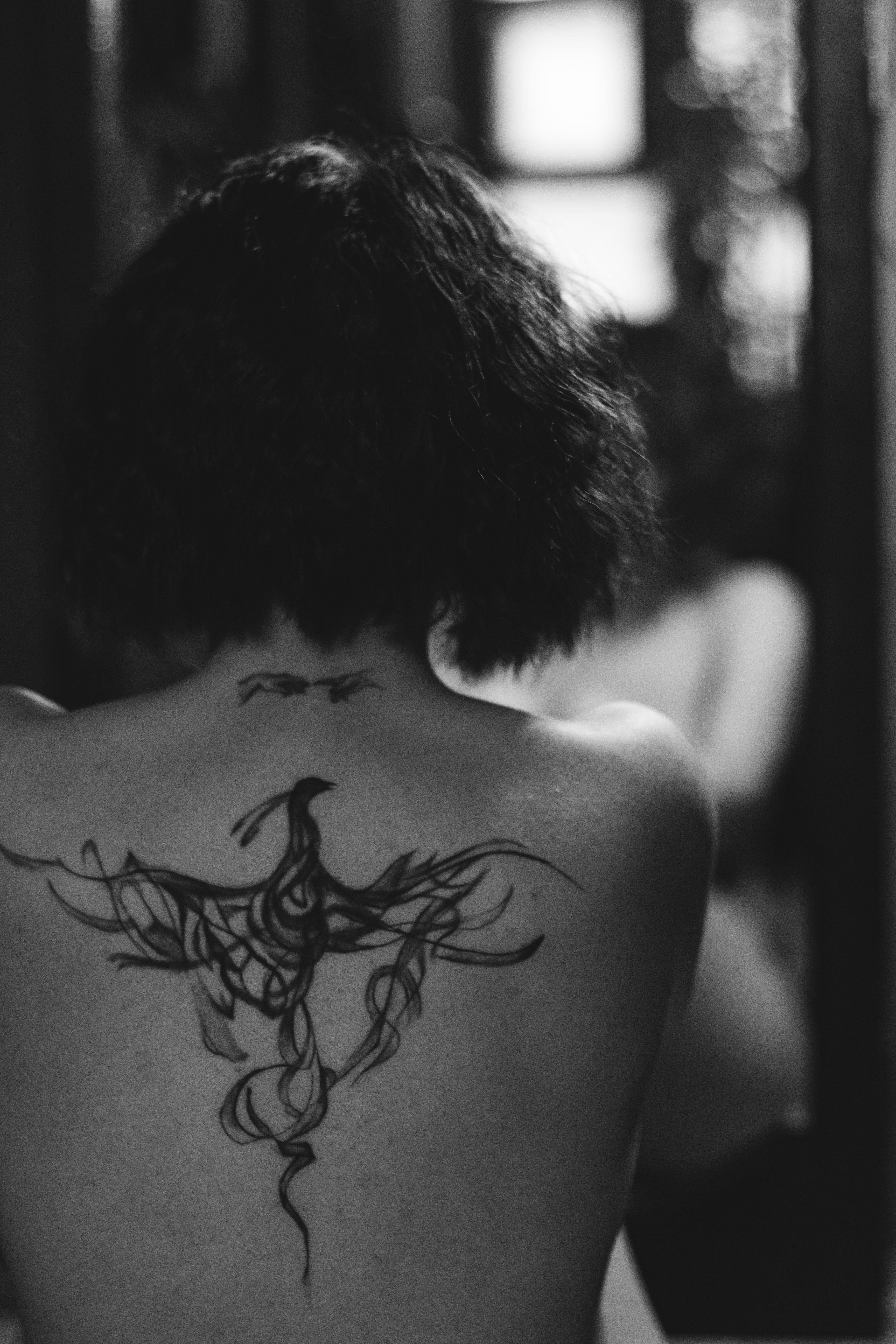 Tatuagem de fênix em fineline blackwork nas costas com asas abertas